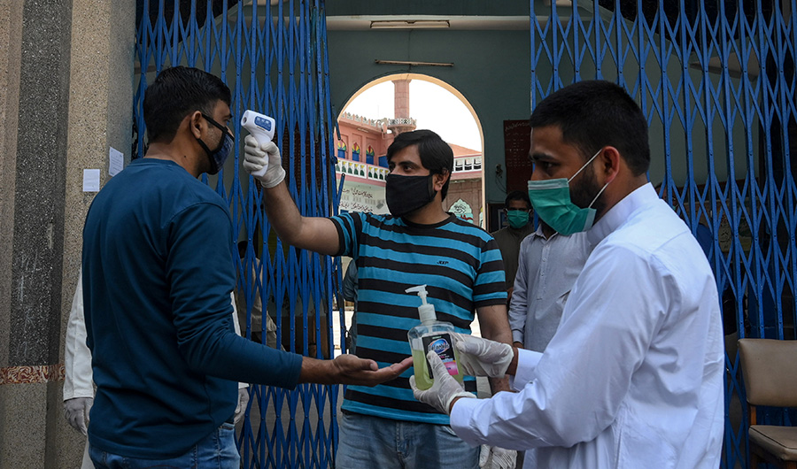 A Muslim devotee (C) checks the body temperature of a worshipper arriving to offer Friday prayers at a mosque in Lahore on April 24, 2020. (AFP)