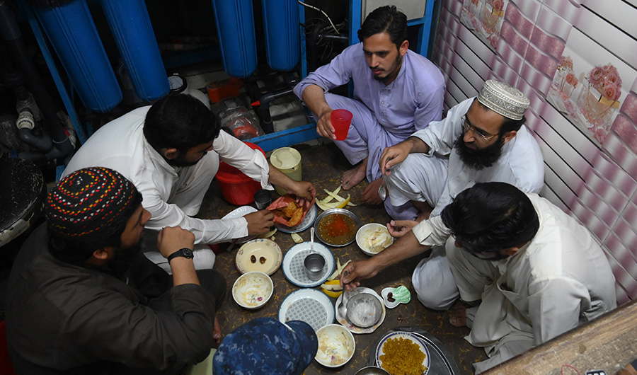 Muslim devotees break their fast at a shop on the Islamic holy month of Ramadan during a government-imposed nationwide lockdown as a preventive measure against the COVID-19 coronavirus, along a street in Lahore on April 29, 2020. (AFP)