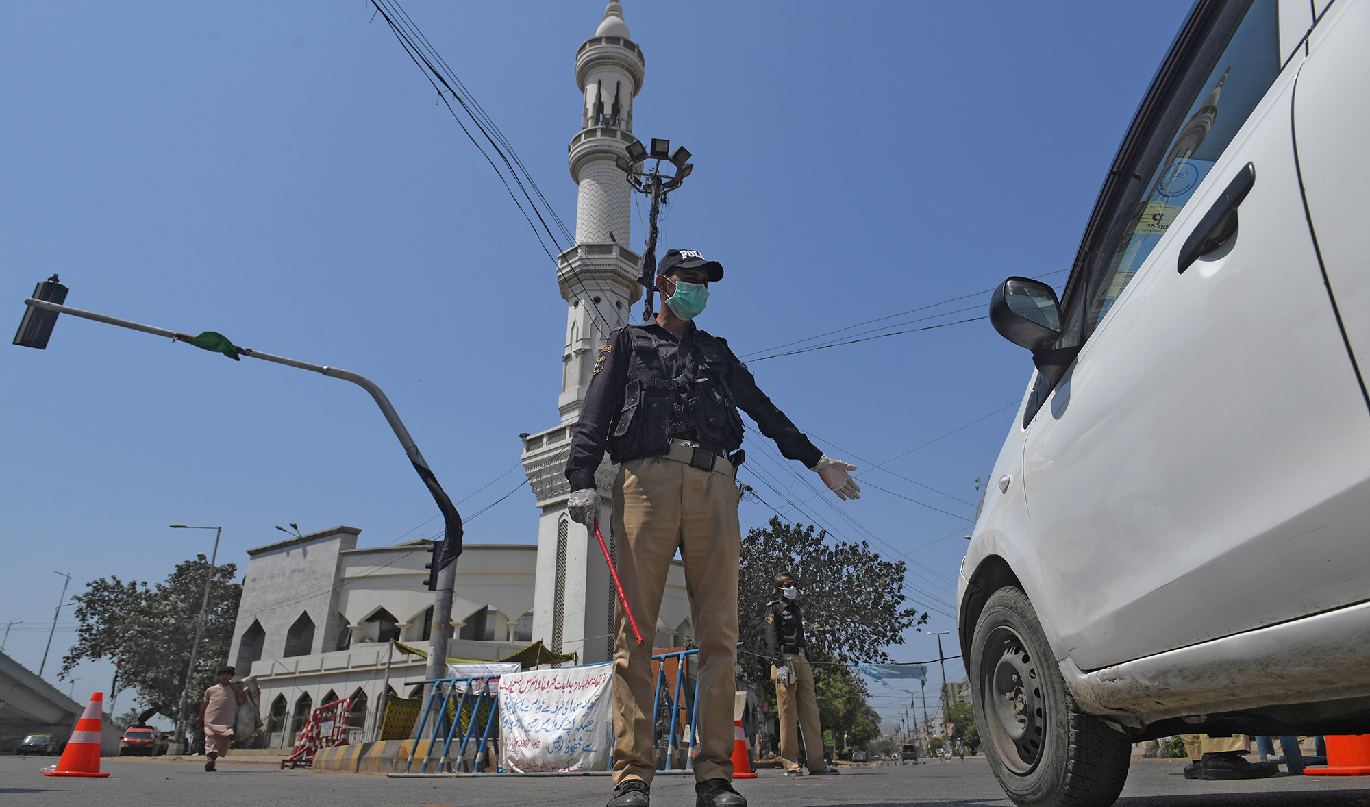 In this file photo, a policeman wearing a facemask stop a commuter beside a closed mosque during Friday prayers on a government-imposed nationwide lockdown as a preventive measure against the COVID-19 coronavirus, in Karachi on April 17, 2020. (AFP)