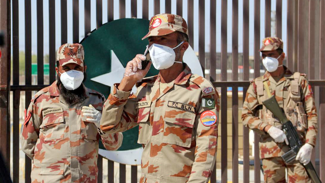 In this file photo, paramilitary soldiers wear face masks as they stand in front of a closed gate of Pakistan's border post, after Pakistan sealed its border with Iran as a preventive measure following the coronavirus outbreak, at the border post in Taftan on Feb. 25, 2020. (REUTERS)