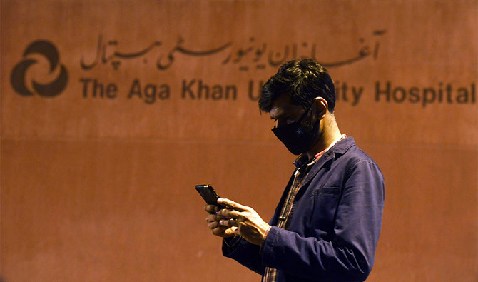 A Pakistani journalist wearing a protective facemask uses his mobile phone outside the Aga Khan University Hospital where a patient of the COVID-19 novel coronavirus has been admitted in Karachi on February 26, 2020. (AFP)