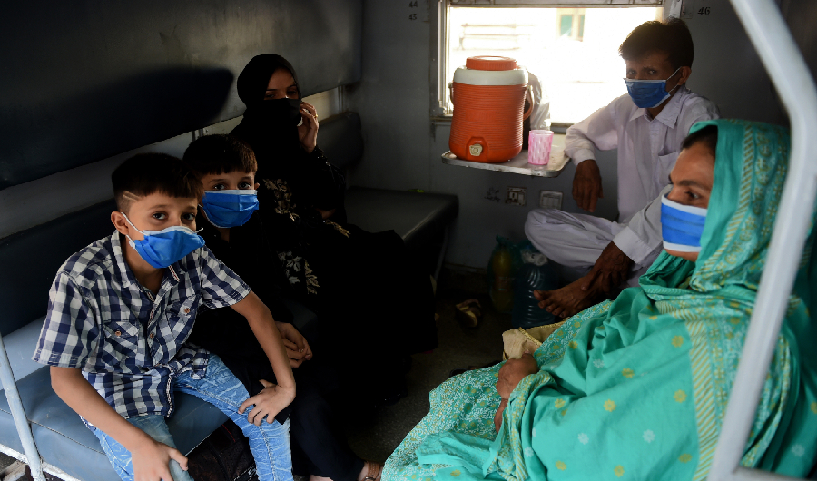 Passengers wearing facemasks sit in a carriageat the Karachi cantonment railway station as train services resumed ahead of the Muslim Eid al-Fitr festival after the government eased a nationwide lockdown imposed as a preventive measure against the COVID-19 coronavirus, in Karachi on May 20, 2020. (AFP)