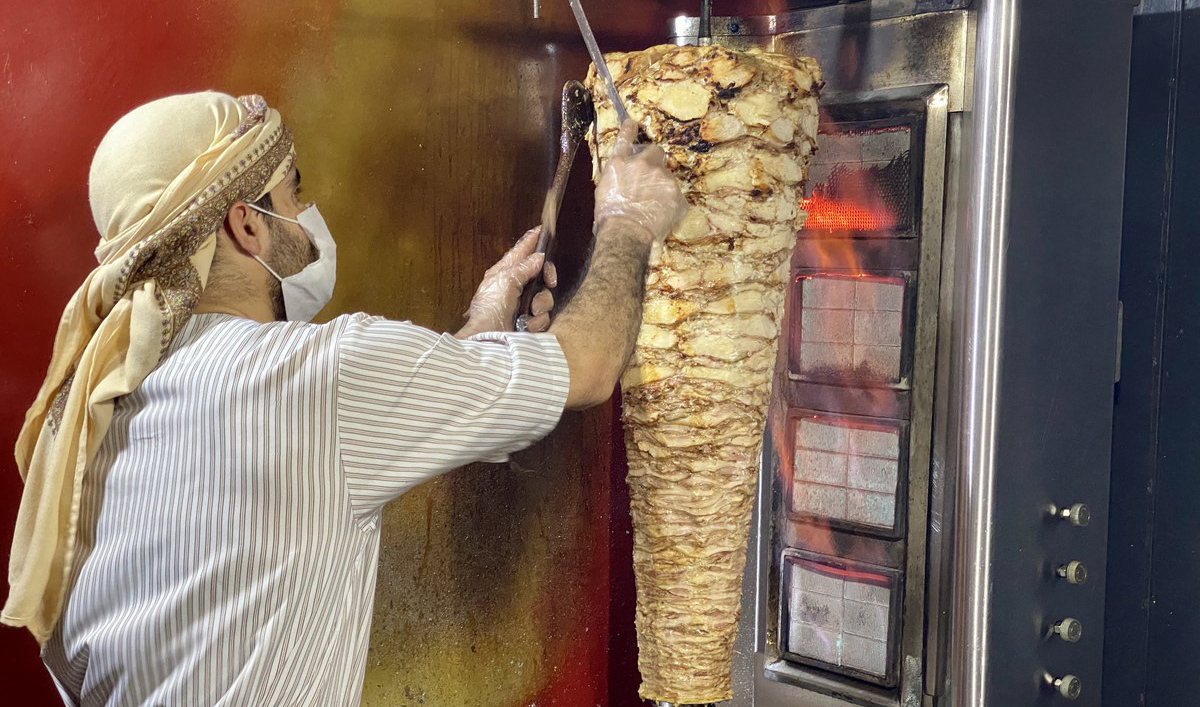 Abu Amir, a Syrian Shawarma maker is busy cutting fresh slices of meat for parcels at his food kiosk in F-10 area of Islamabad on May 20, 2020. (AN photo)