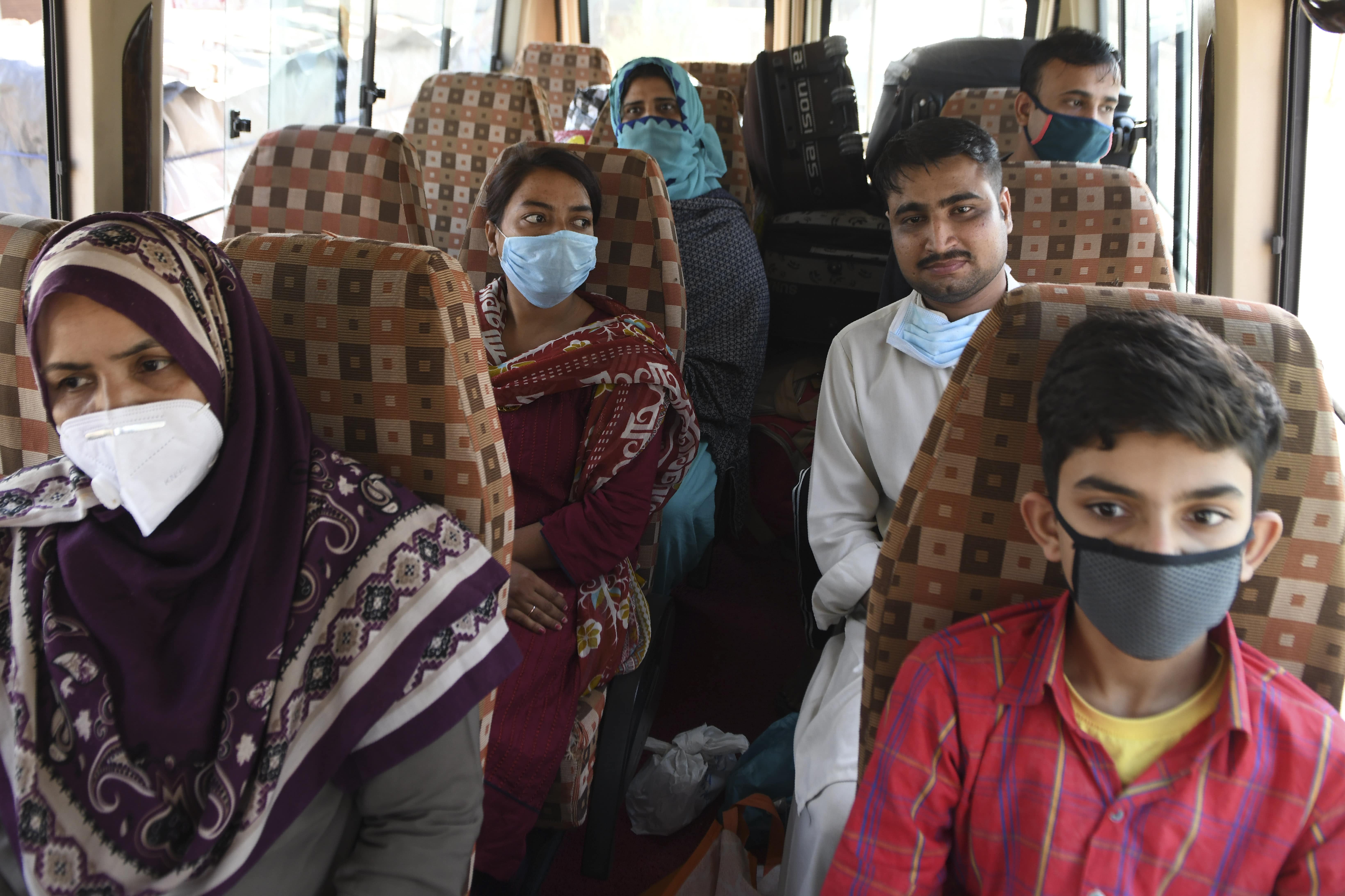 Pakistani nationals, who were stranded in India following the closure of borders due to the COVID-19 coronavirus lockdown, sit inside a mini bus before crossing the India-Pakistan Wagah border post, some 35 kms from Amritsar on May 27, 2020. (AFP)