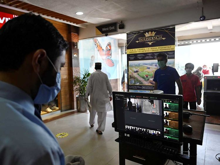 In this picture taken on May 18, 2020 people wearing facemasks walk past a thermal scanner at the entrance of the Centaurus Mall after the government eased a nationwide lockdown imposed as a preventive measure against the COVID-19 coronavirus, in Islamabad. (AFP)