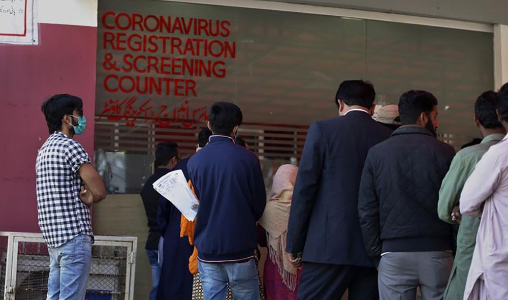 A Pakistani looks at a banner that lists precautions for the new coronavirus, while he and others wait their turn at a coronavirus registration and screening counter, at the Pakistan Institute of Medical Sciences Hospital, in Islamabad on March 17, 2020. (AP/File)