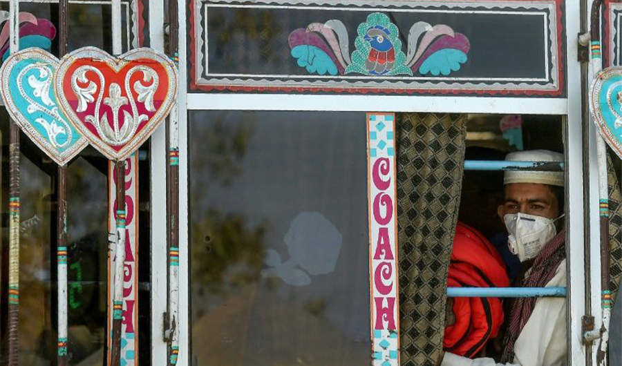 A passenger wearing a facemask as a prevention measure against the coronavirus sits in a bus in Karachi on March 11, 2020. (AFP)