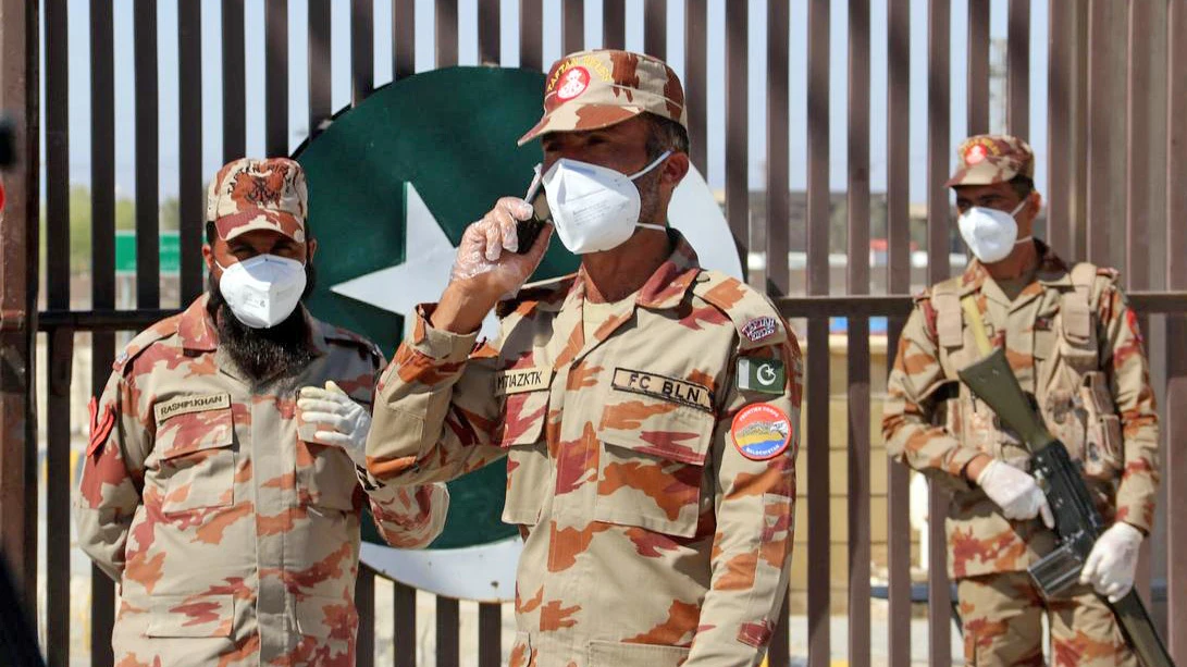 In this file photo, paramilitary soldiers wear face masks as they stand in front of a closed gate of Pakistan's border post, after Pakistan sealed its border with Iran as a preventive measure following the coronavirus outbreak, at the border post in Taftan on Feb. 25, 2020. (REUTERS)