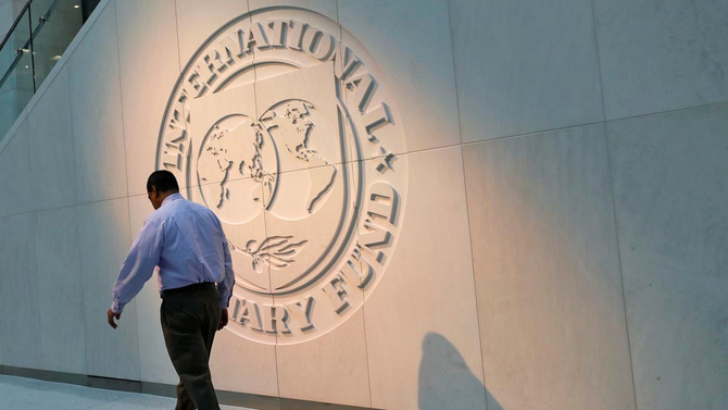 In this file photo, a man walks past the International Monetary Fund (IMF) logo at its headquarters in Washington, US on May 10, 2018. (REUTERS)