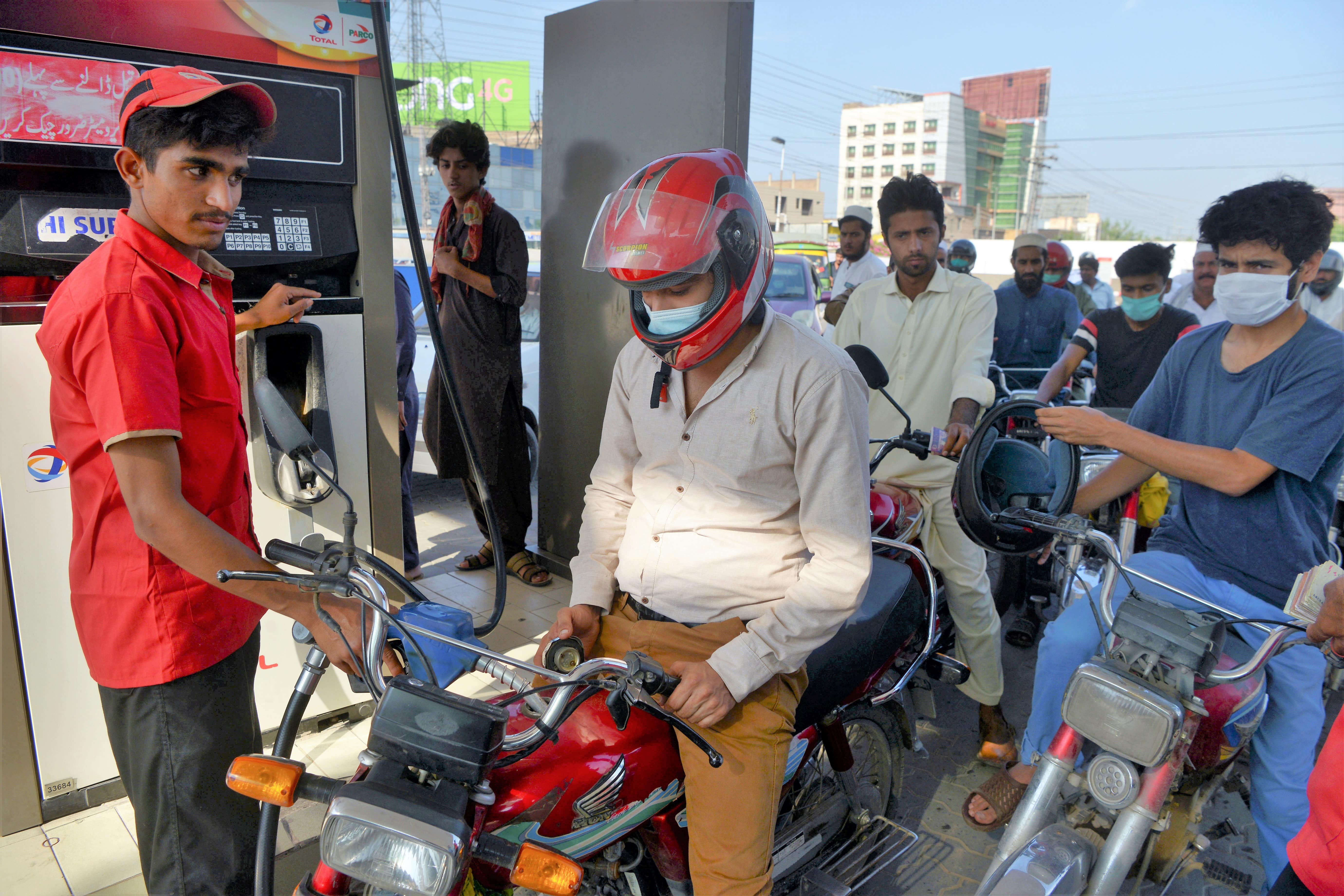 Commuters wait to fill their vehicles tanks at a gasoline station as Pakistan's government reduced prices of petroleum due a decrease of the global oil market, in Peshawar on June 2, 2020. (AFP)
