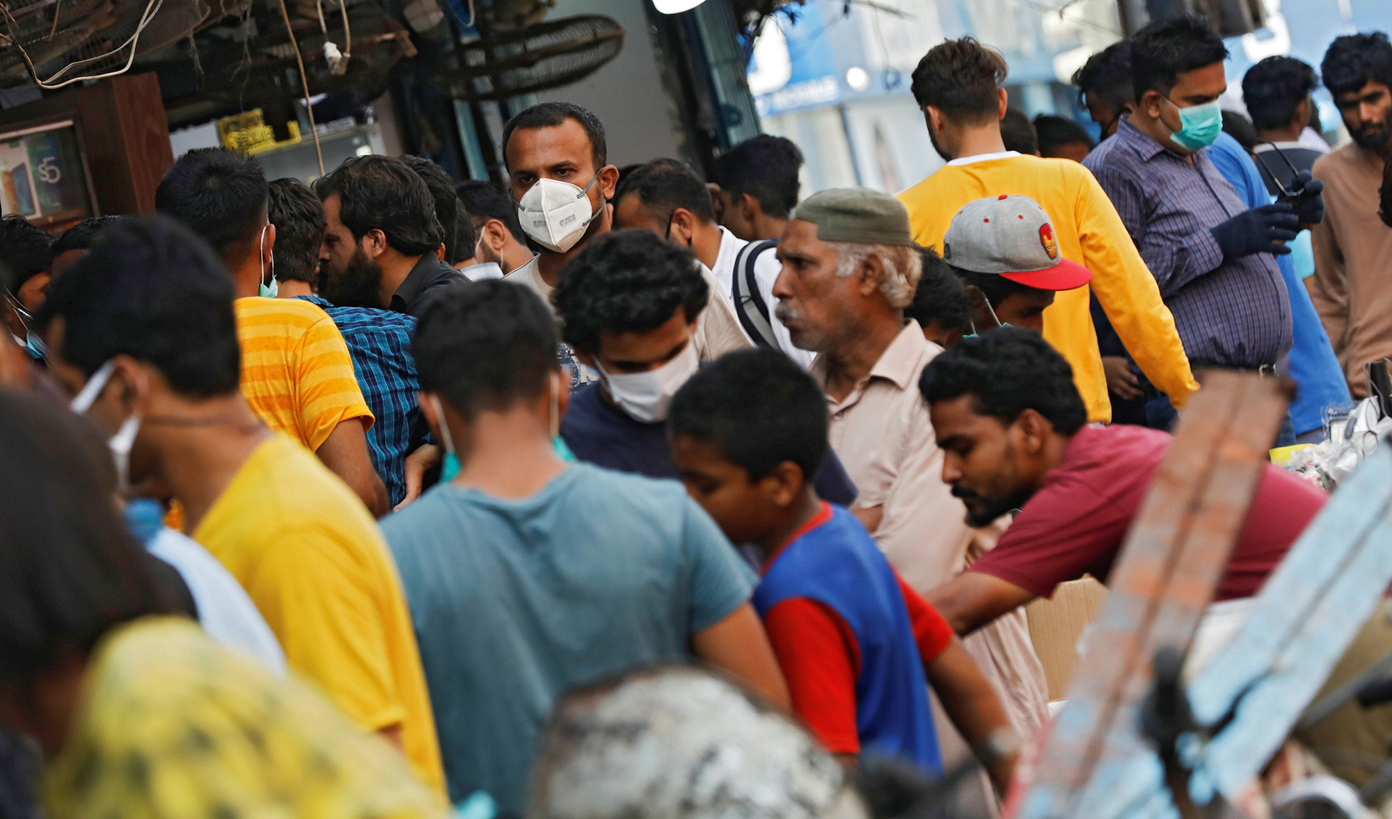 A man wearing a protective face mask walks amidst the rush of people outside an electronics market, after Pakistan started easing the lockdown restrictions, as the outbreak of the coronavirus disease (COVID-19) continues, in Karachi on June 4, 2020. (REUTERS)