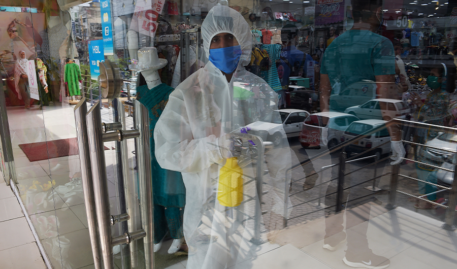 A shopkeeper wearing Personal Protective Equipment (PPE) holds a disinfectant at the entrance of a shop after the government eased the nationwide lockdown imposed as a preventive measure against the COVID-19 coronavirus, in Rawalpindi on May 11, 2020. (AFP)