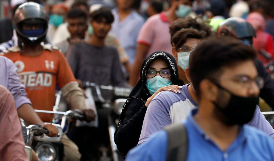 A woman rides on a motor bike as she wears a protective face mask amid the rush of people outside a market as the outbreak of the coronavirus disease (COVID-19) continues, in Karachi, Pakistan June 8, 2020. (REUTERS)