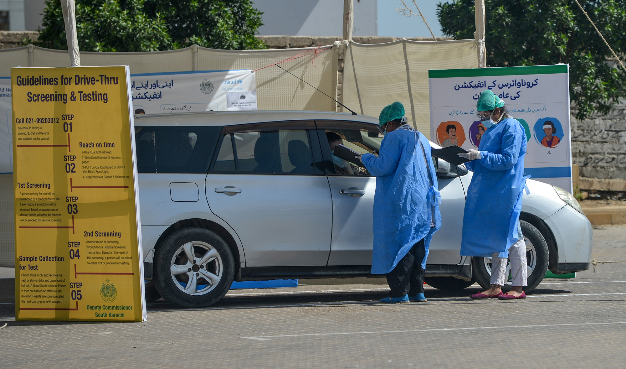In this file photo, medical staff members wearing protective gear take information from a resident sitting in a car for a coronavirus test at a drive-through screening and testing facility point during a government-imposed nationwide lockdown as a preventive measure against the COVID-19 coronavirus, at the port city of Karachi on April 4, 2020. (AFP)