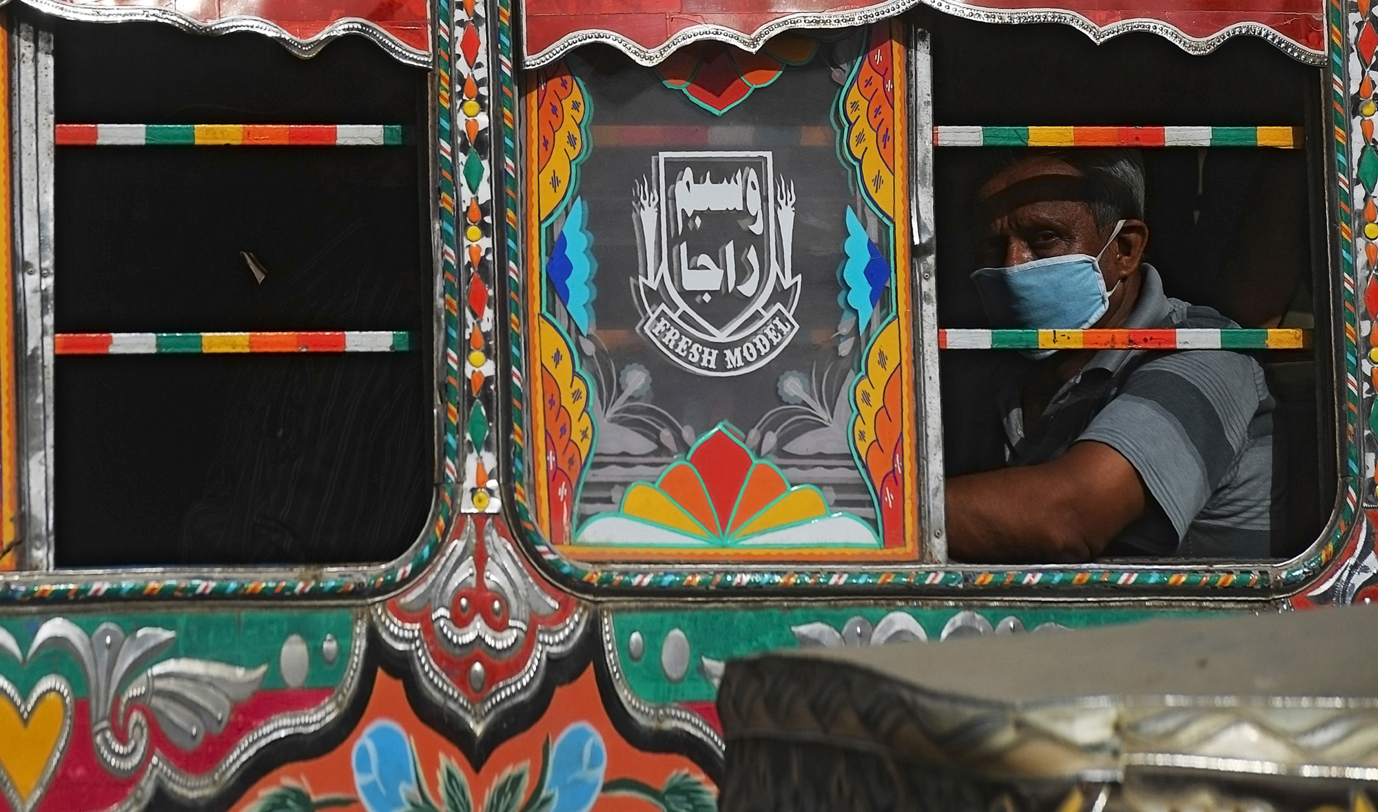 A passenger waring a facemask sits on a bus in a street in Karachi on June 8, 2020. Pakistan has recorded more than 100,000 cases of coronavirus, health authorities said on June 8, as hospitals warned they are running out of beds to treat patients. (AFP)