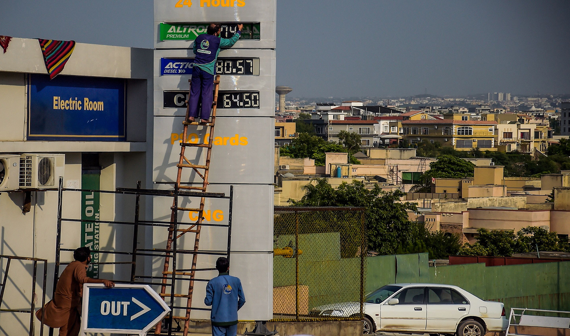 An employee fixes the oil prices on a billboard at a gas station in Rawalpindi on June 10, 2020. (AFP)