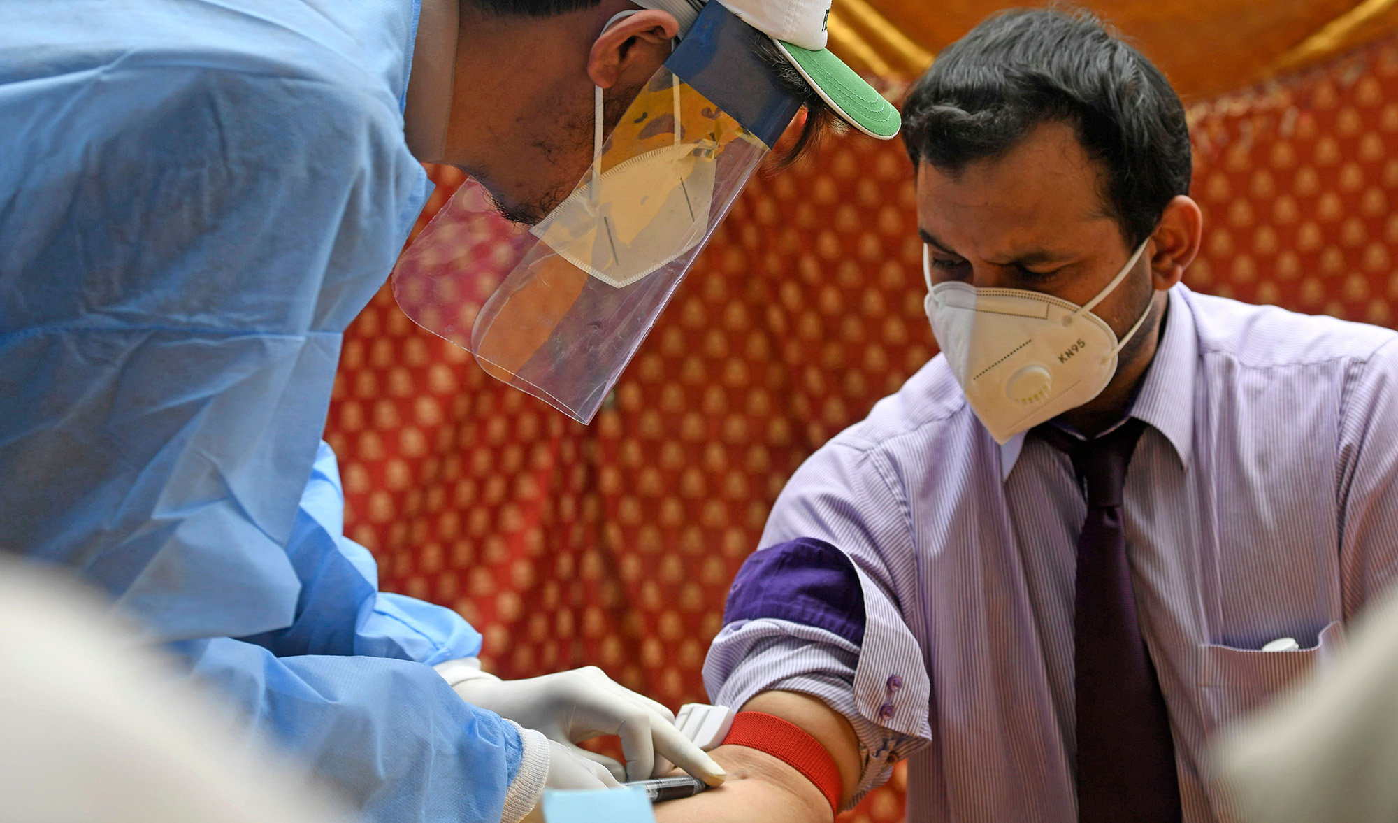A health official wearing protective gear takes blood sample of a man at a drive-through screening and testing facility for the COVID-19 coronavirus, alongside a street in Islamabad on June 10, 2020. (AFP)