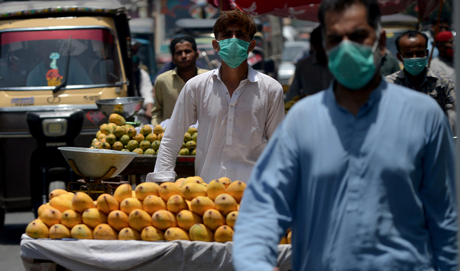 Vendors wearing facemasks walk along a street in Karachi on June 16, 2020. (AFP)