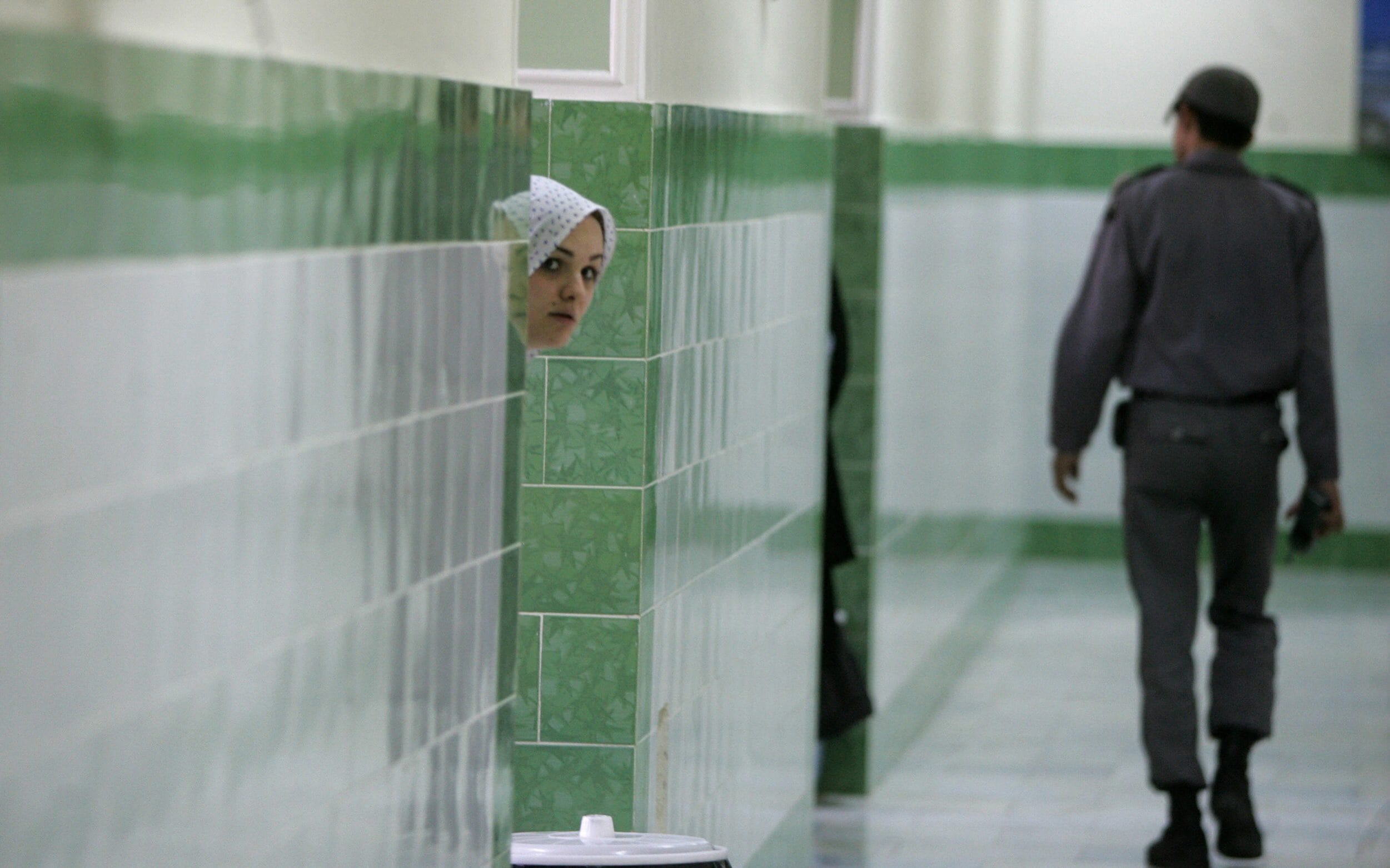 In this 2006 file photo, an Iranian inmate peers from behind a wall as a guard walks by at the female section of the infamous Evin jail. (AFP)
