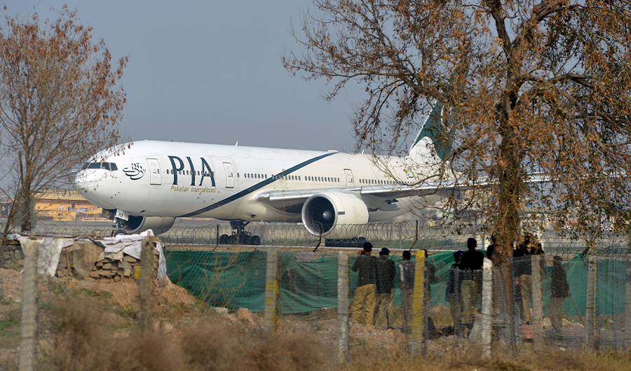 Pakistan policemen stand guard as a Pakistan International Airline (PIA) plane taxis on the runway in Islamabad on February 8, 2016. (AFP)
