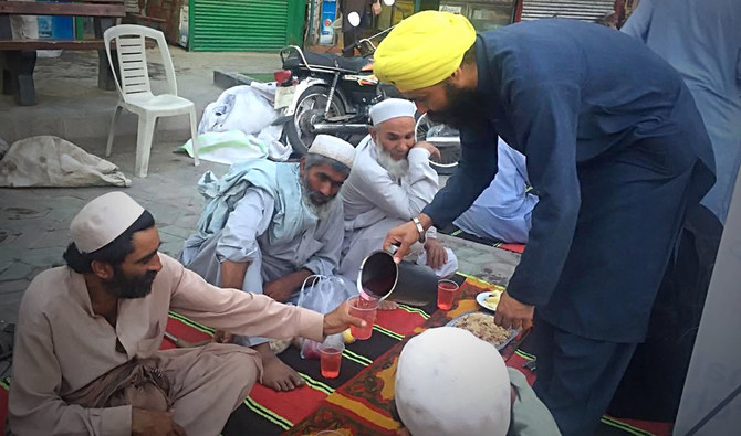 A young Sikh community leader in a yellow turban pours cold drinks for Muslims gathered in Peshawar for a sundown iftar meal hosted by the Sikh community during Ramadan on Thursday, May 16, 2019. (AN photo)