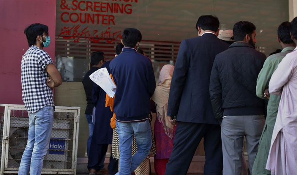 In this file photo, people wait for their turn on a coronavirus registration and screening counter in Pakistan Institute of Medical Sciences hospital in Islamabad on March 17, 2020. (AP)