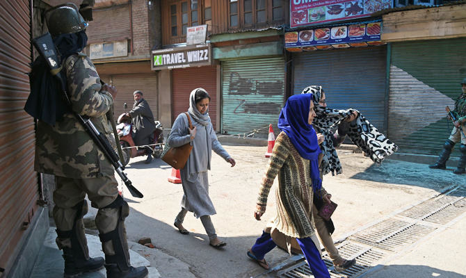 Indian paramilitary troopers stand guard as Kashmiri women walk past during the enforcement on restrictions of movement in Srinagar on March 10, 2019. (AFP)