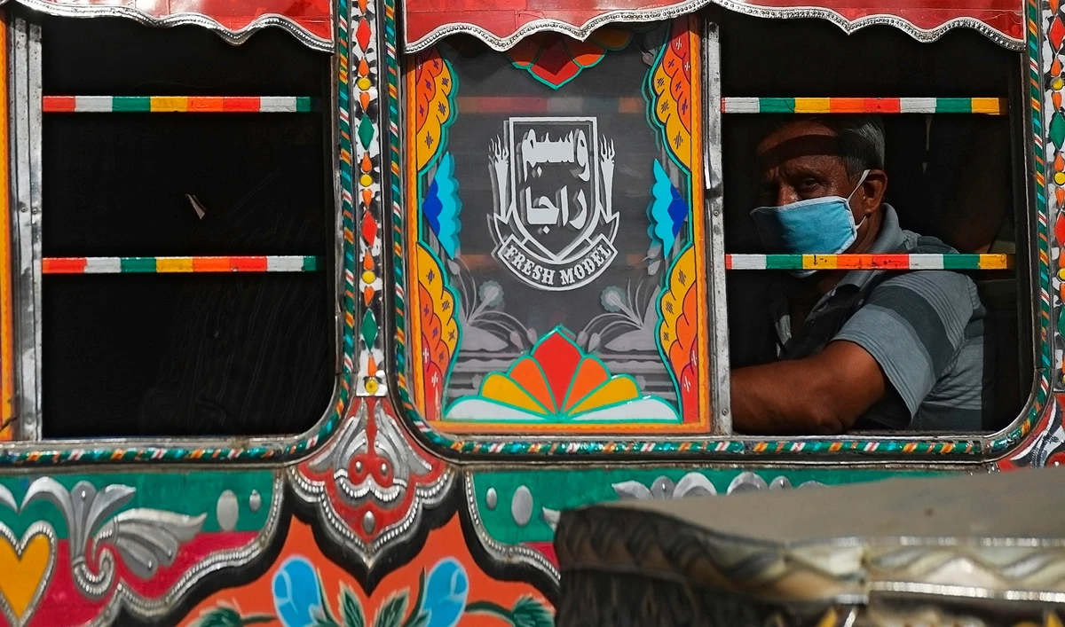 A passenger waring a facemask sits on a bus in a street in Karachi on June 8, 2020. Pakistan has recorded more than 100,000 cases of coronavirus, health authorities said on June 8, as hospitals warned they are running out of beds to treat patients. (AFP)