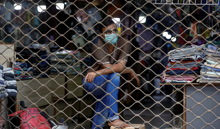 A garment seller wears a protective face mask as he waits for customers behind the roller shutter of a market, as the outbreak of the coronavirus disease (COVID-19) continues, in Karachi, Pakistan June 15, 2020. (REUTERS)