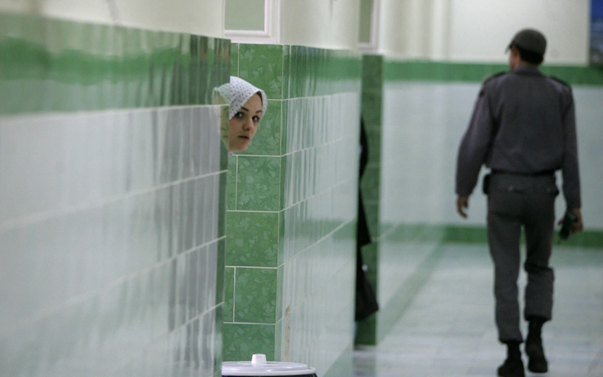 In this 2006 file photo, an Iranian inmate peers from behind a wall as a guard walks by at the female section of the infamous Evin jail. (AFP)