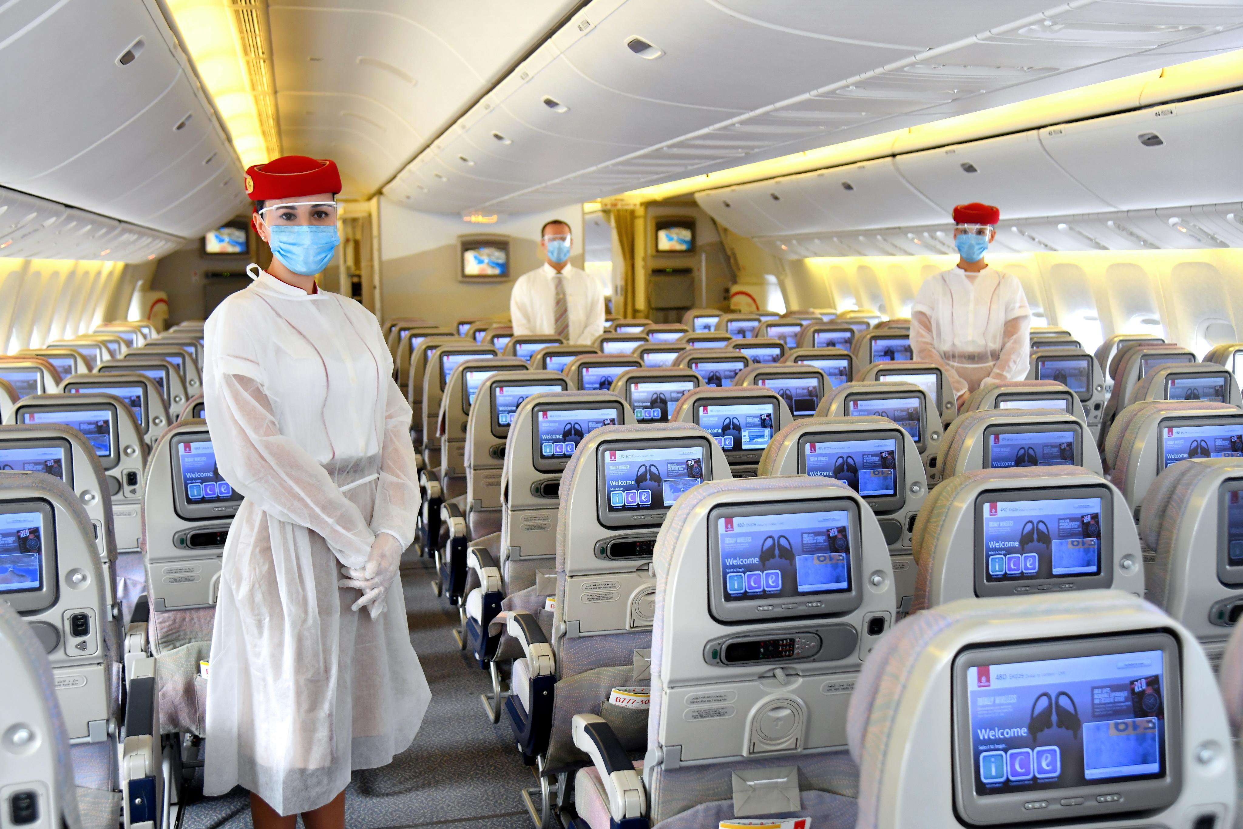 Crew members are seen wearing protective clothes over their uniforms onboard an Emirates airplane, in this April 2020 photo released by the airline to show its coronavirus preparedness. (Photo courtesy: Emirates)
