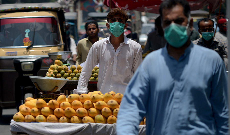Vendors wearing facemasks walk along a street in Karachi on June 16, 2020. (AFP)