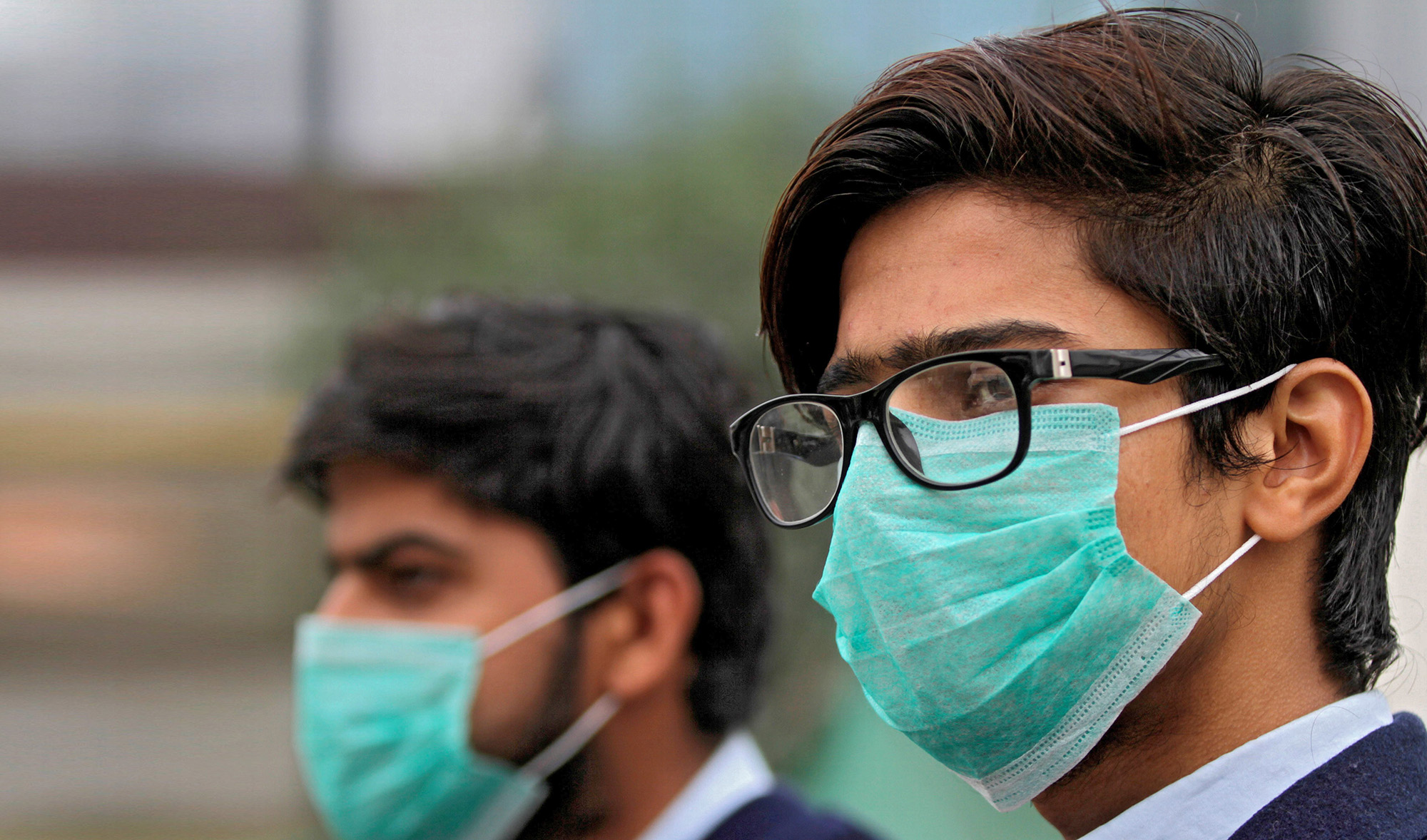 In this file photo, students wearing protective masks wait for a bus in Lahore on Nov. 22, 2019. (REUTERS)