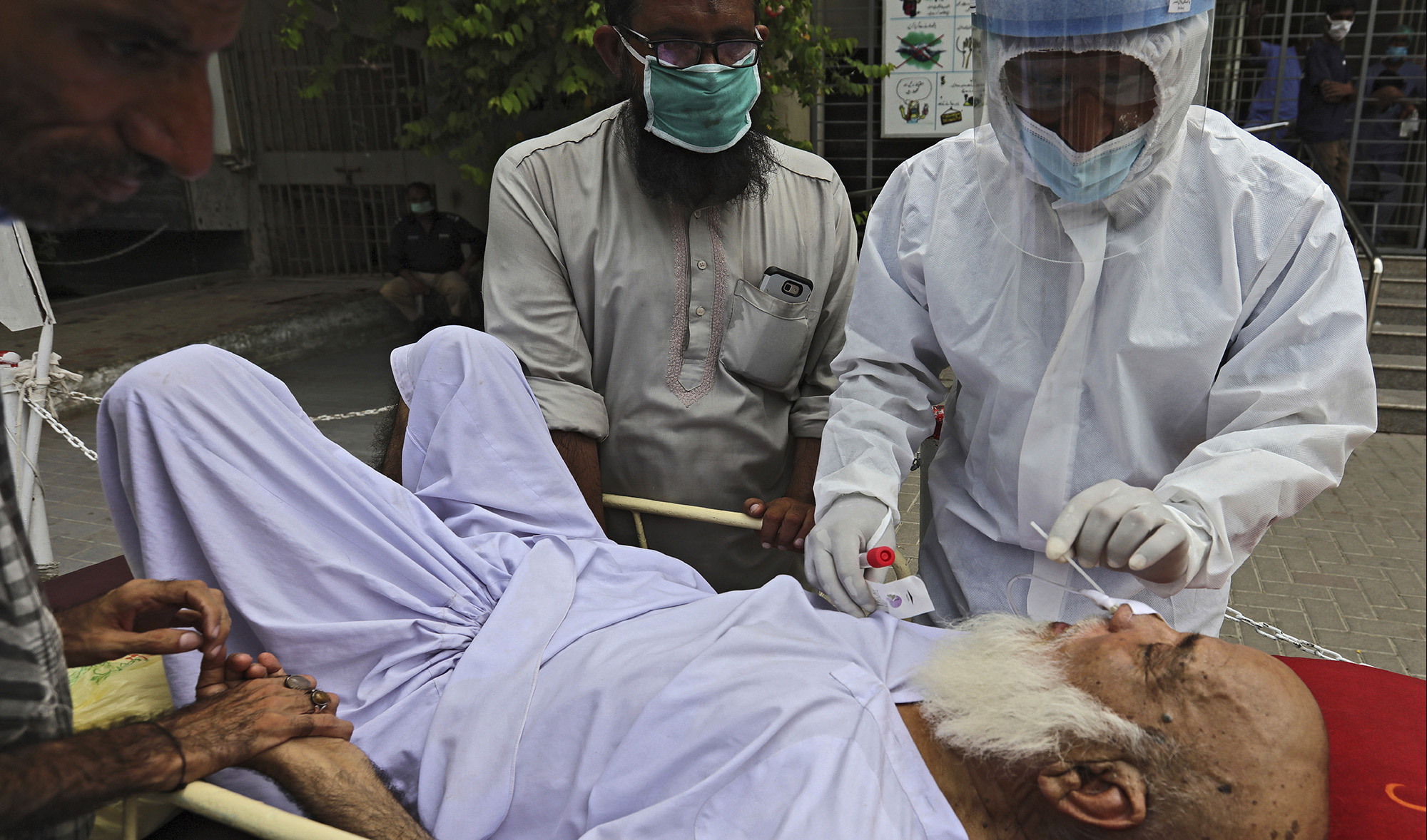 A health worker takes a nasal swab sample from an elderly man at a testing and screening facility for the new coronavirus in a hospital in Karachi on July 17, 2020. (AP)