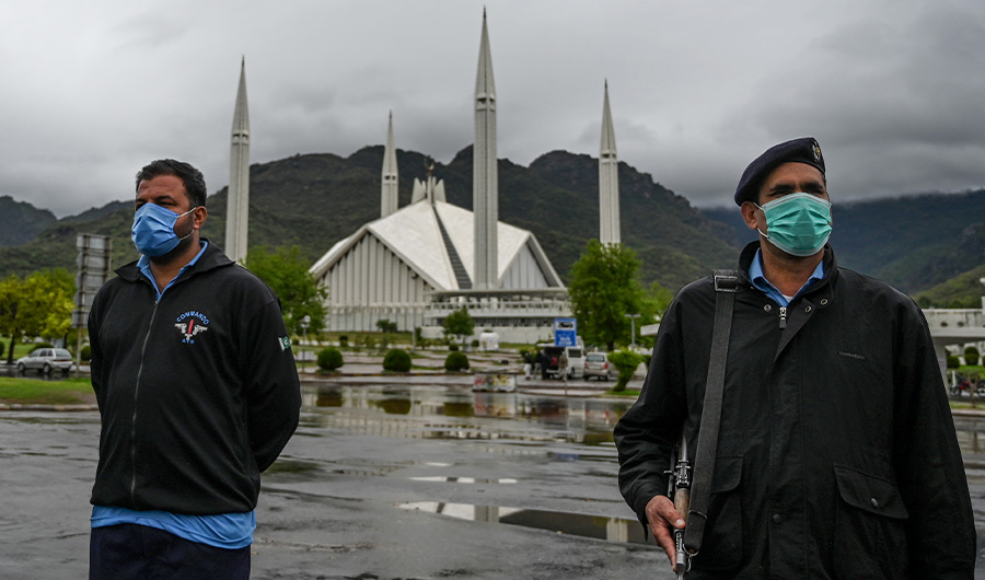 Policemen wearing facemasks stand guard at a checkpoint beside the Grand Faisal Mosque during a government-imposed nationwide lockdown as a preventive measure against the COVID-19 coronavirus, in Islamabad on March 27, 2020. (AFP)