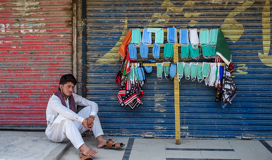 A street vendor selling facemasks sits as he waits for customers on a street in Rawalpindi on July 5, 2020. (AFP)