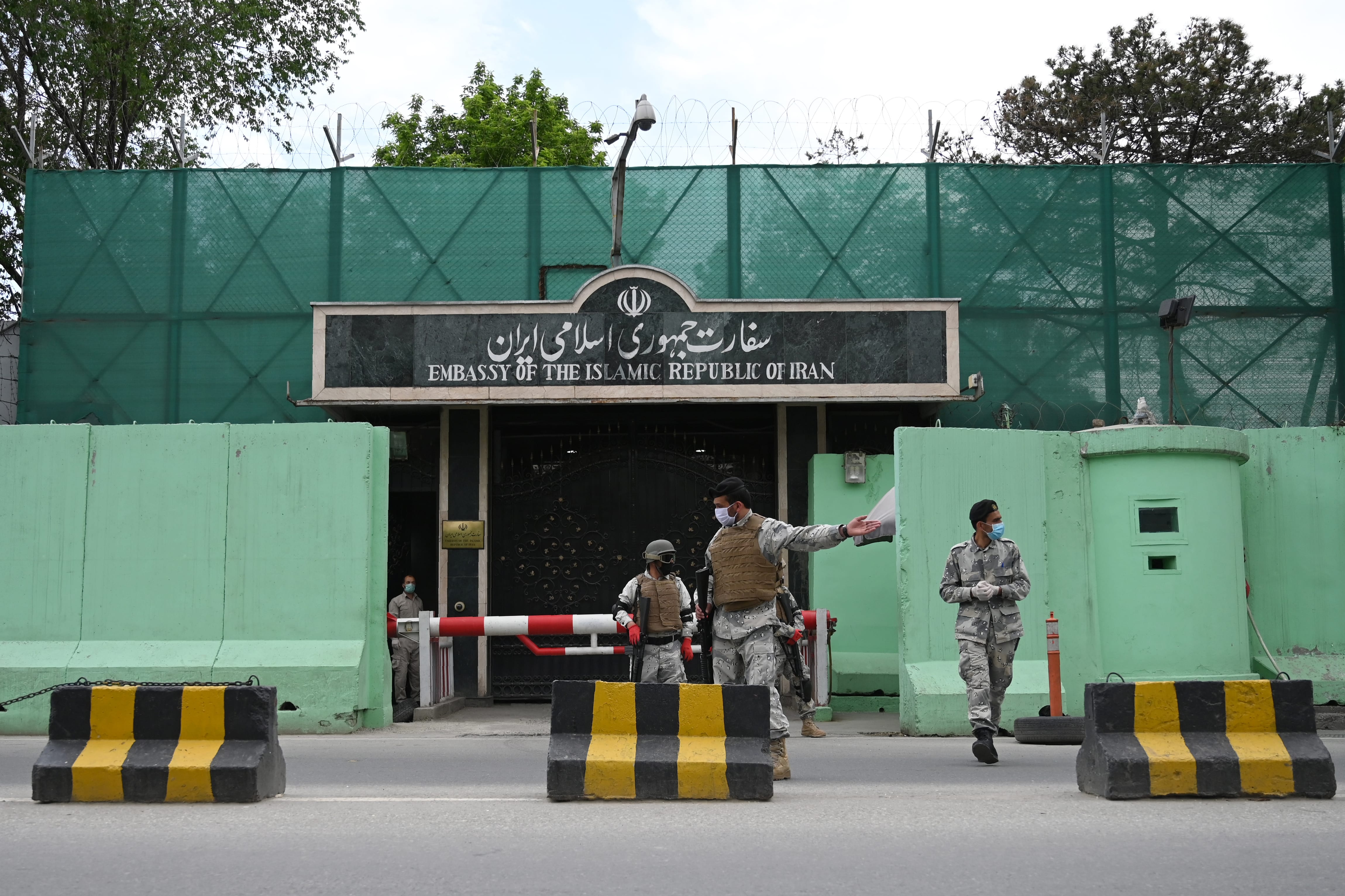 Afghan security personnel stand guard in front of the Iranian embassy as civil society activists hold banners and shout slogans against the Iranian government during a protest, in Kabul on May 11, 2020. Afghanistan on May 01, 2020 has recovered 18 bodies of migrants who were allegedly beaten and tortured before being forced into a river by Iranian border guards. ( AFP photo)
