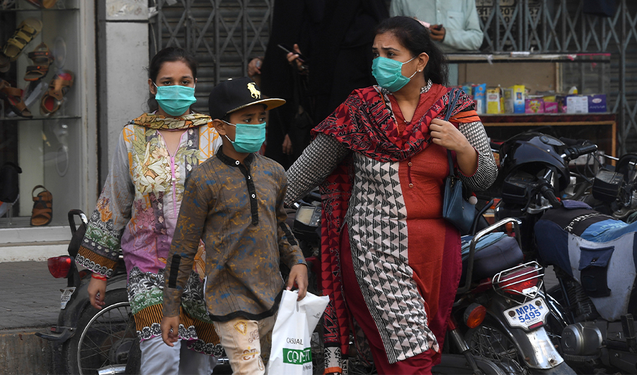 A family waring facemasks cross a street at a market area in Karachi on June 8, 2020. (AFP)