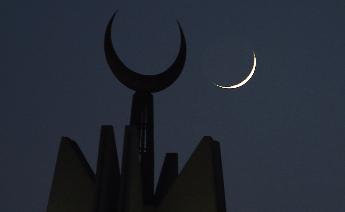 This file photo taken on May 27, 2017 shows the moon rising over the giant Faisal Mosque in Islamabad. (AFP)