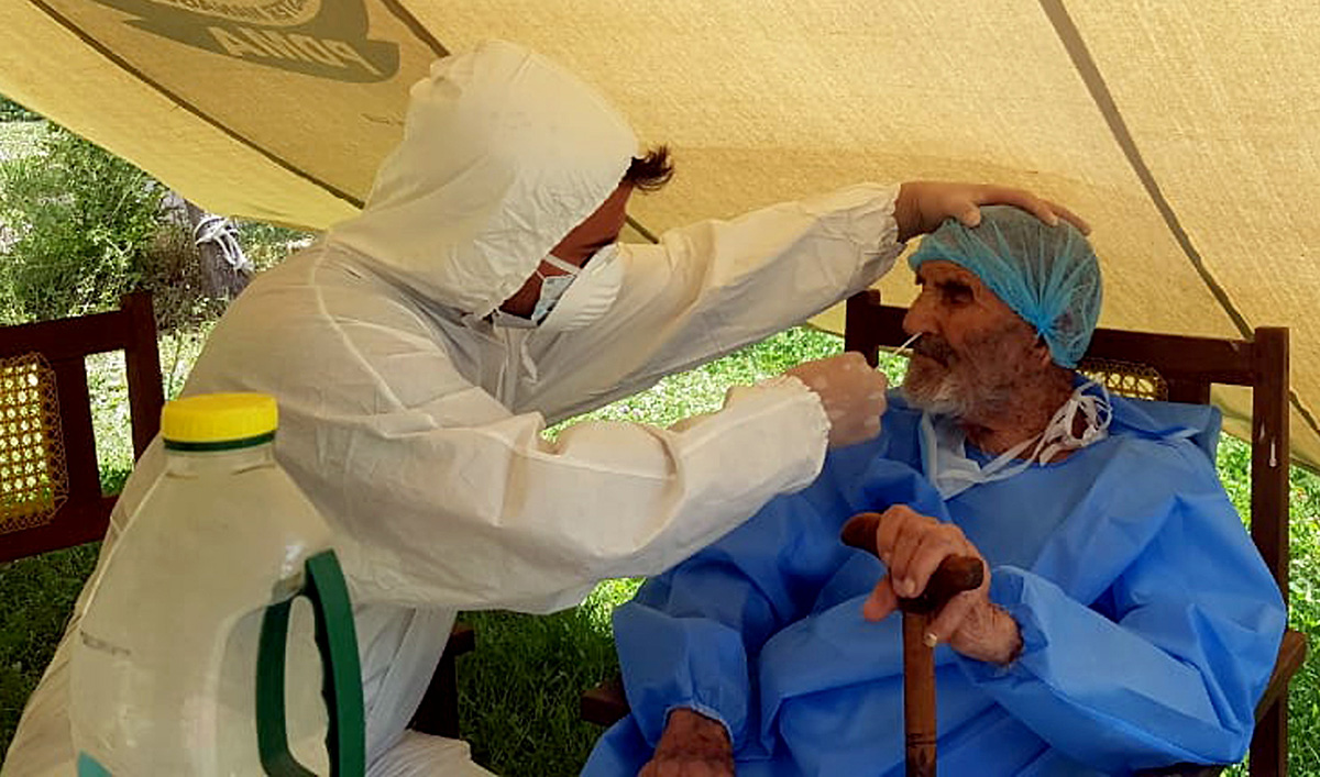 A paramedic wearing protective gear takes a nasal swab of 103 year-old Abdul Alim, to be tested for the coronavirus disease (COVID-19), at the Aga Khan Health Services Emergency Response Centre in Booni, Chitral, Pakistan in this undated photograph provided to Reuters. (Suhail Aziz/Handout via REUTERS)