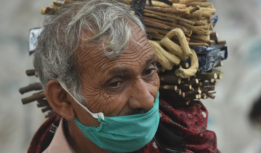 A miswak, teeth cleaning twig, street vendor looks for customers along a street in Lahore on July 12, 2020. (AFP)