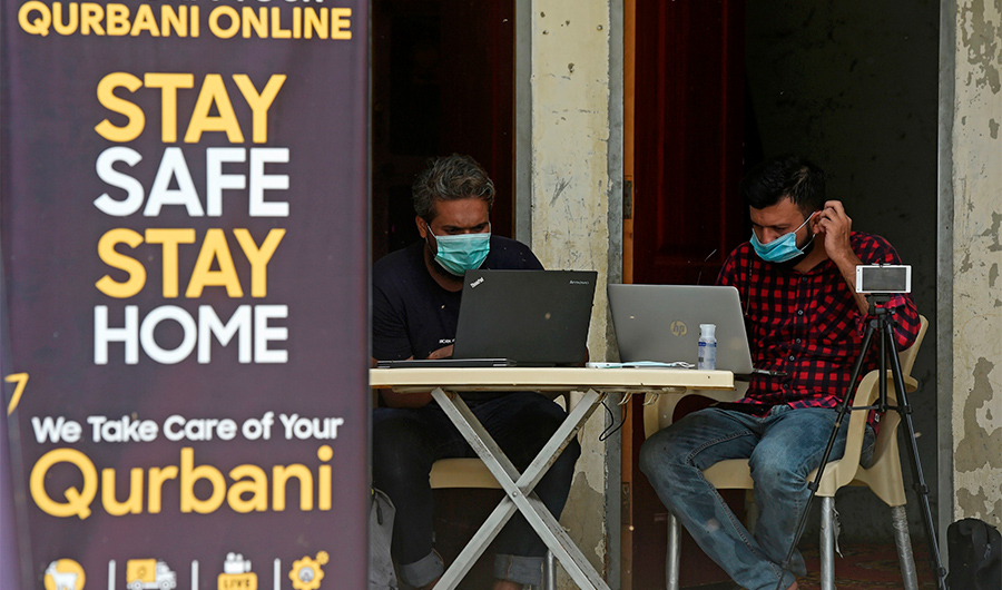 In this picture taken on July 22, 2020 Aqib Mughal (L) and Yasir Iqbal, who runs a website that sells goats through online to customers, upload pictures of goats on their website ahead of the Muslim festival Eid al-Adha or the 'Festival of Sacrifice', at a farm in Pakistan's port city of Karachi. (AFP)