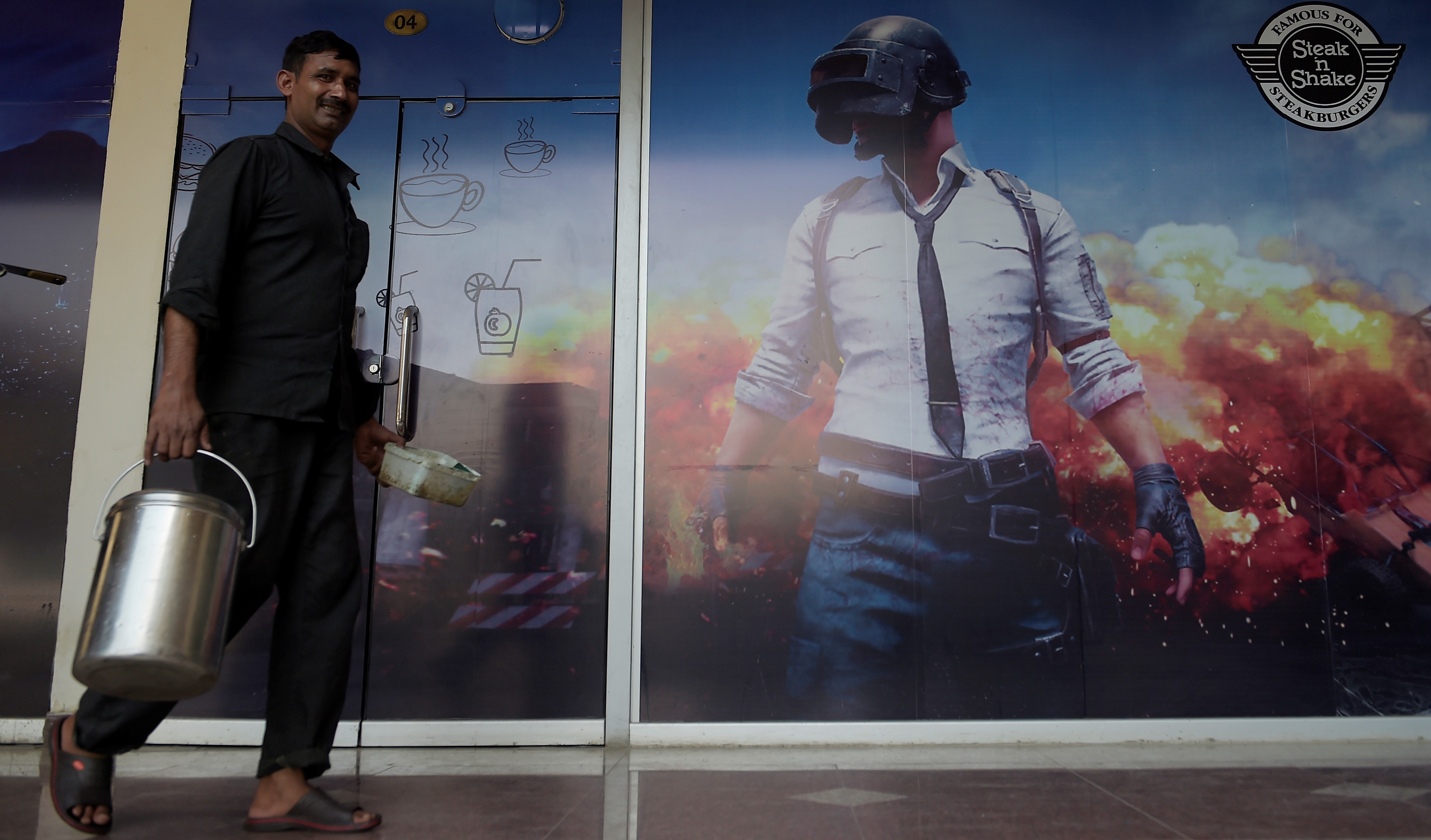 A man walks past a poster of online game Player Unknown's Battlegrounds (PUBG) in Rawalpindi on July 13, 2020. - Pakistan on July 2 temporarily blocked the hugely popular online game PlayerUnknown's Battlegrounds (PUBG) after receiving complaints it was addictive and following media reports linking the brutal, multiplayer shoot 'em up to suicide. (AFP photo)