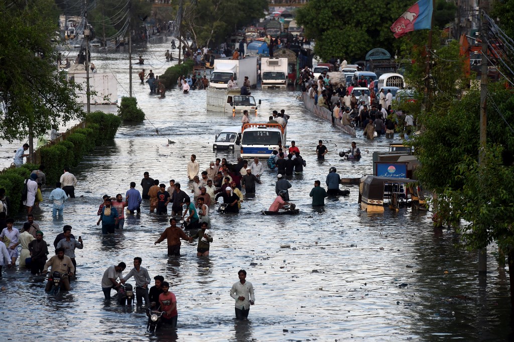 Commuters cross a flooded street after heavy monsoon rains in the Pakistan's port city of Karachi on July 27, 2020. (AFP)