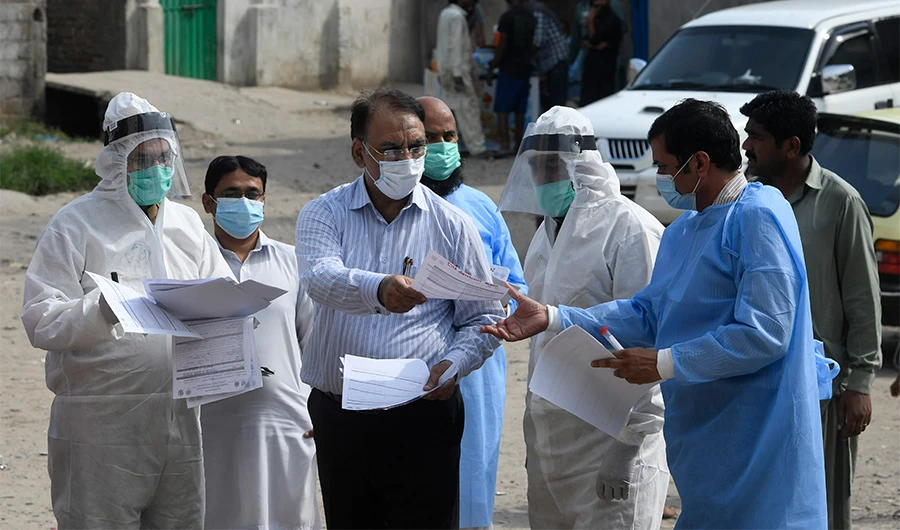 Health officials wearing Personal Protective Equipment (PPE) hold medical records collected form residents after taking samples for COVID-19 coronavirus during a door-to-door screening and testing operation at a slum area in Islamabad on June 30, 2020. (AFP)