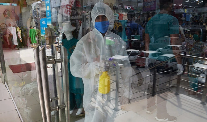 A shopkeeper wearing Personal Protective Equipment (PPE) holds a disinfectant at the entrance of a shop after the government eased the nationwide lockdown imposed as a preventive measure against the COVID-19 coronavirus, in Rawalpindi on May 11, 2020. (AFP)