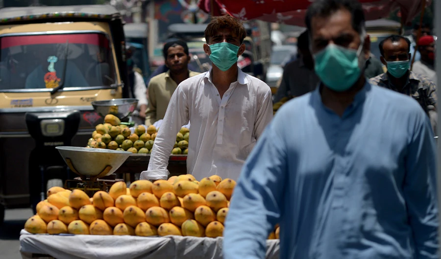 Vendors wearing facemasks walk along a street in Karachi on June 16, 2020. (AFP)