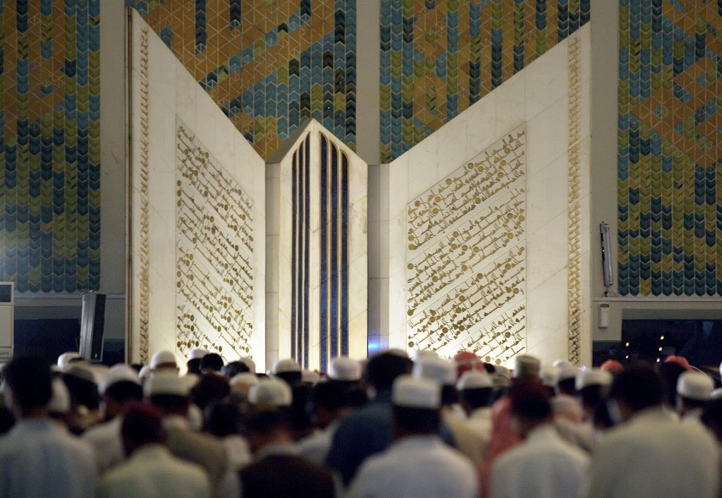 Pakistani Muslims offer prayers in front of the giant Qur'an at the Faisal Mosque in Islamabad, Oct. 20, 2006. (AFP/File)