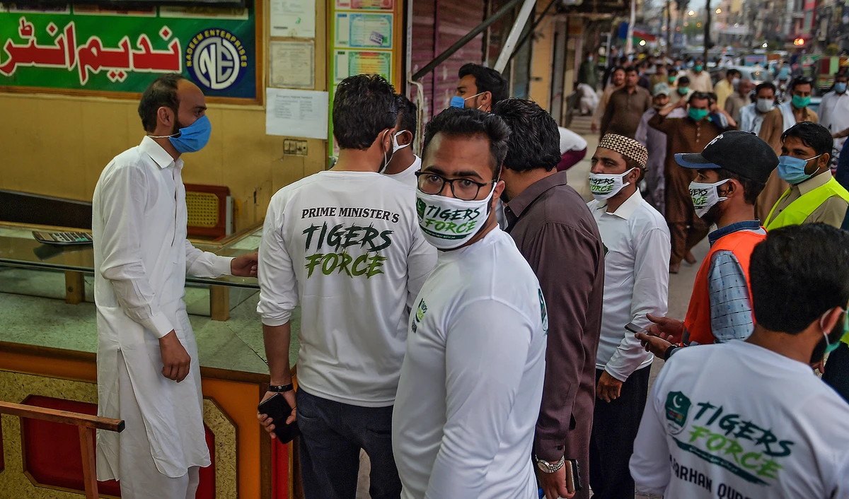 Members of Prime Minister Imran Khan's Corona Relief Tiger Force speak to a shopkeeper as part of their COVID-19 awareness campaign at Raja Bazar in Rawalpindi, June 10, 2020. (AFP/File)