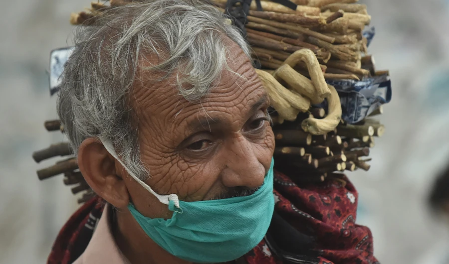 A miswak, teeth cleaning twig, street vendor looks for customers along a street in Lahore on July 12, 2020. (AFP)